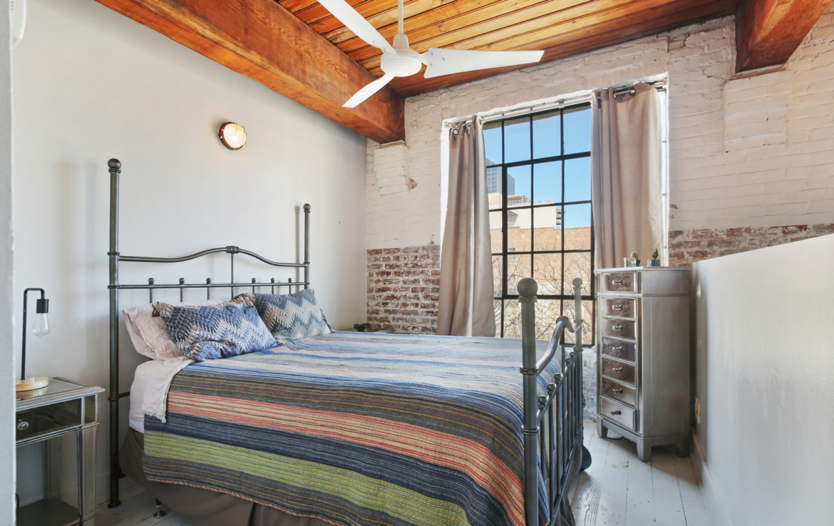 Bedroom with exposed wood ceiling and exposed brick details