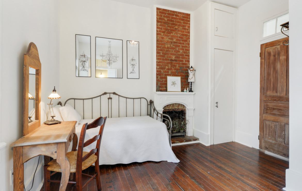 Furnished bedroom with exposed brick and fireplace