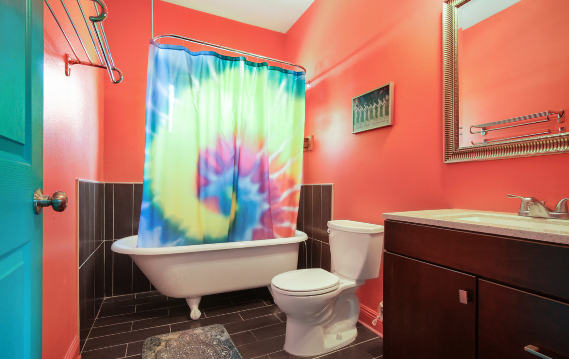 Bathroom with tie-dye shower curtain, toilet, and sink vanity