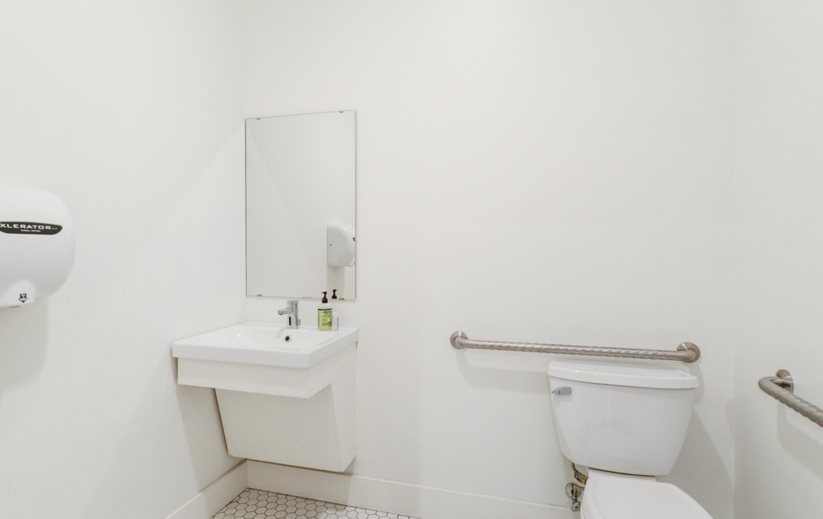 White bathroom with sink, hand dryer, and toilet