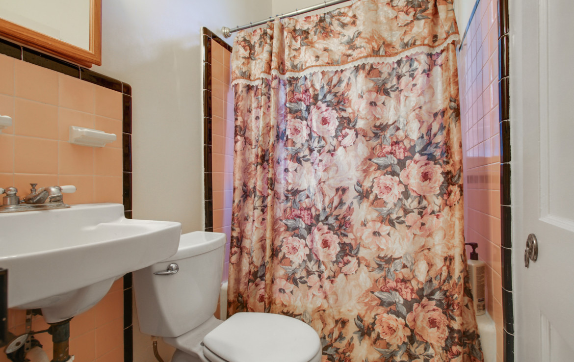Bathroom with floral shower curtain , toilet, and sink