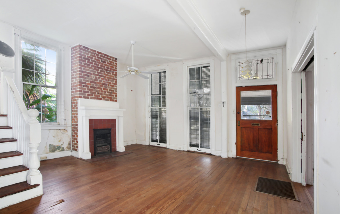 Unfurnished room with exposed brick and fireplace