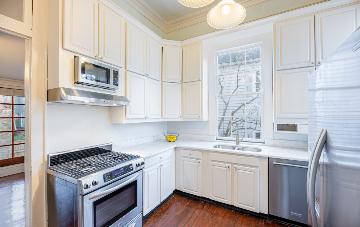 Angle view of kitchen with white cabinets and stainless steel appliances
