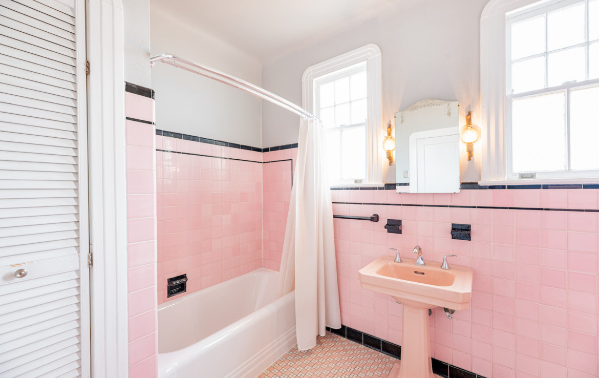 Pink tiled bathroom with sink and tub