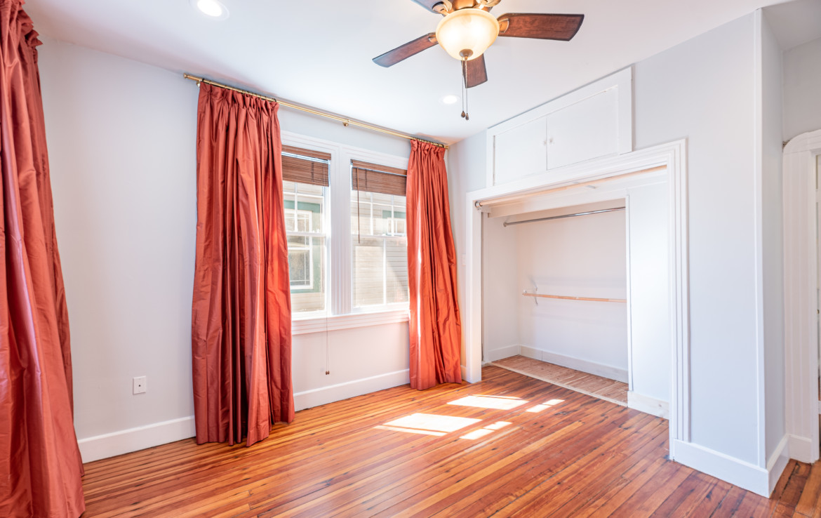 Unfurnished white room with orange curtains and opened closet door