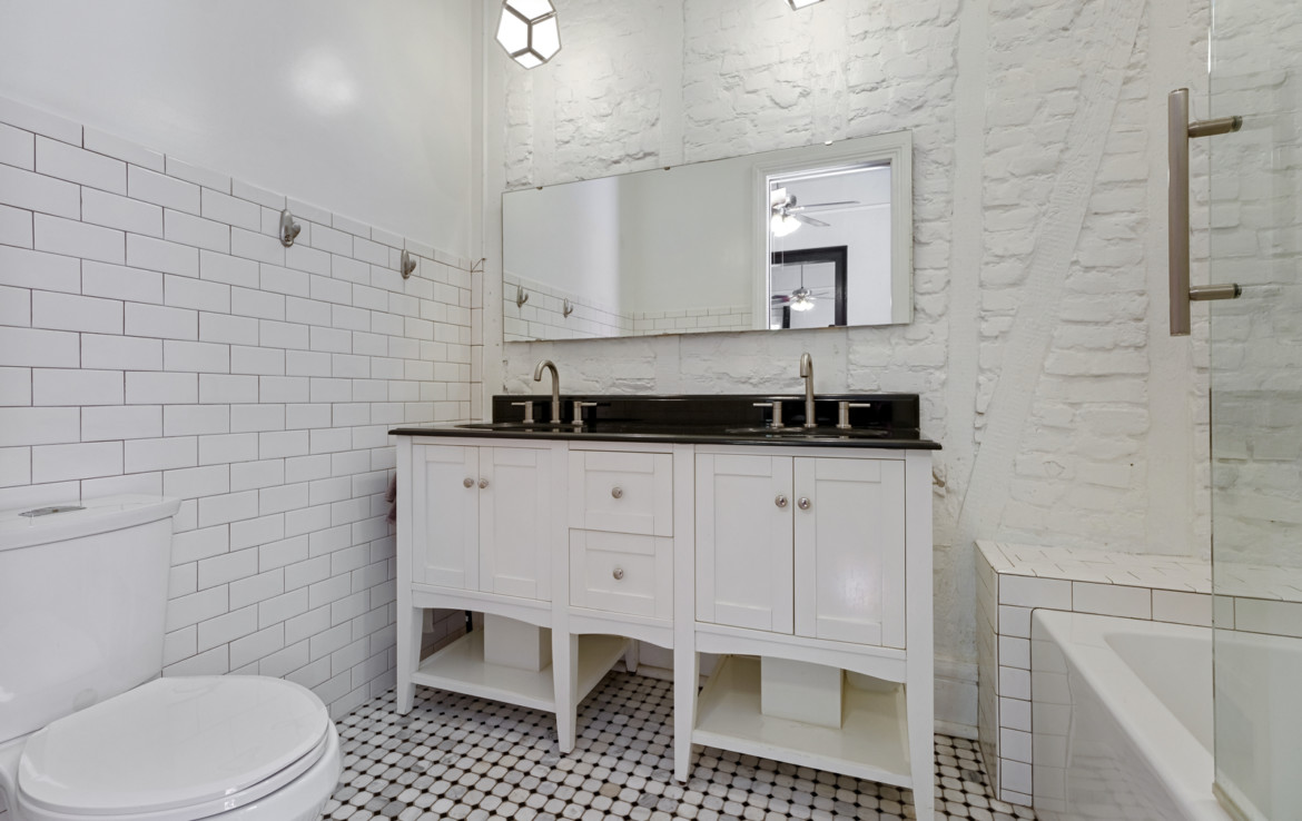 bathroom with twin vanity sinks, toilet and tub