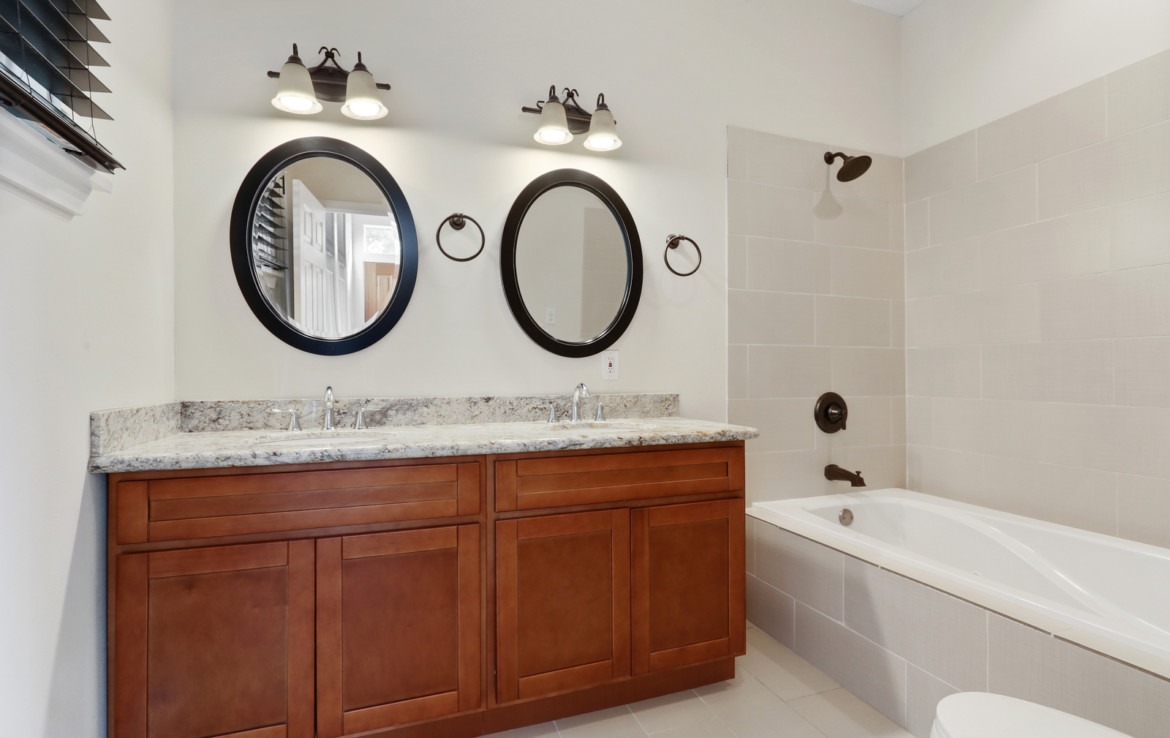 bathroom with twin vanity sinks and tub