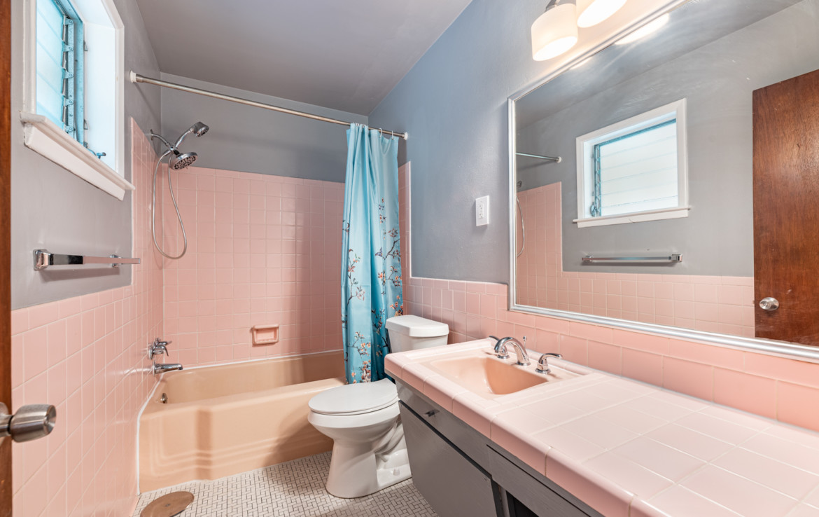 pink tiled bathroom with toilet, sink and tub