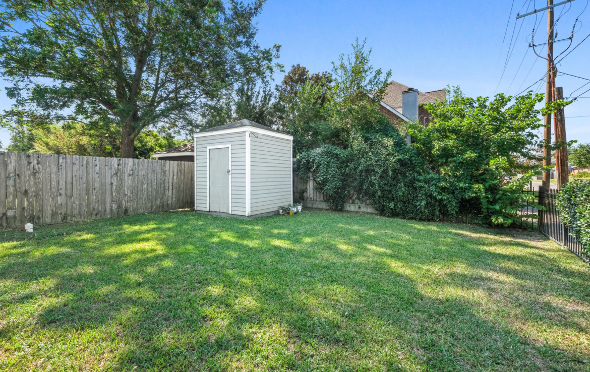 fenced in backyard with grass and shed