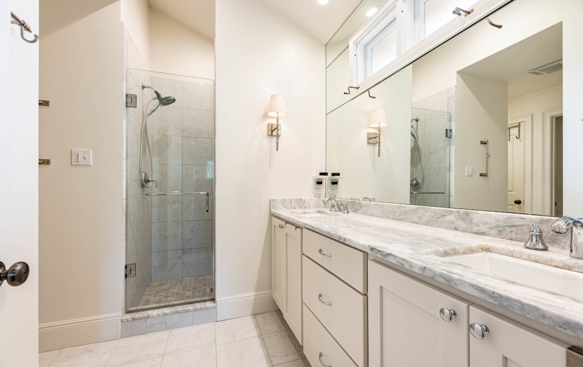 bathroom with twin vanity sinks and walk in shower